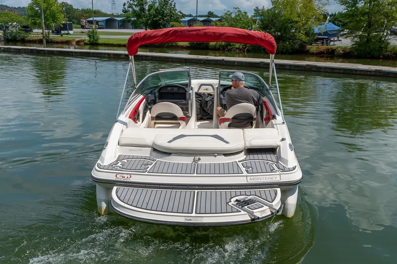 Slide: The Image of 2013 Monterey 204FS boat cruising on a calm lake with a red canopy. - 7
