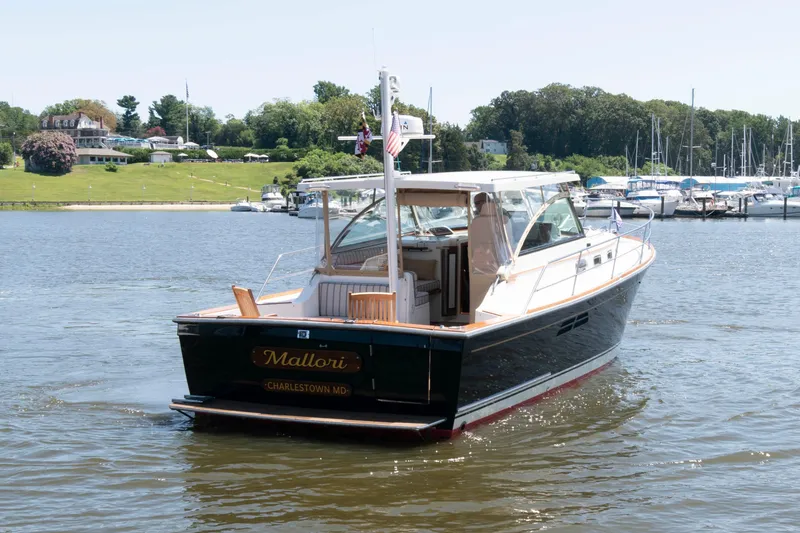 Slide: The Image of 1998 Sabre 36 Hardtop Express boat on water near marina and green landscape. - 5