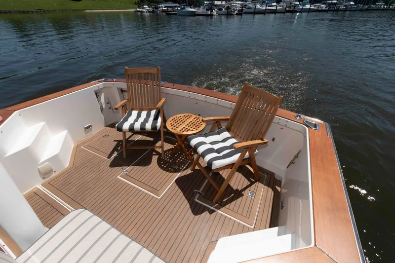 Slide: The Image of 1998 Sabre 36 Hardtop Express deck with chairs and table on calm water. - 6