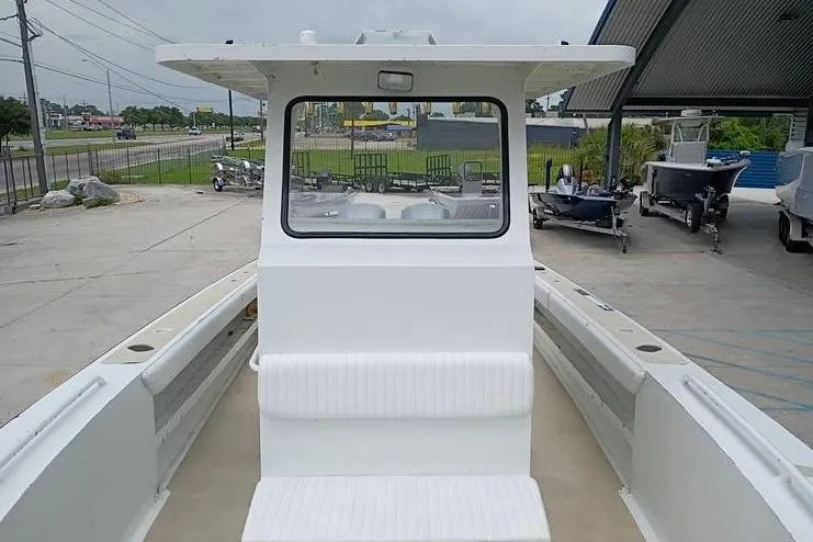 Slide: The Image of 2005 INTIMIDATOR 32 CC boat with center console and seating, parked outdoors. - 14