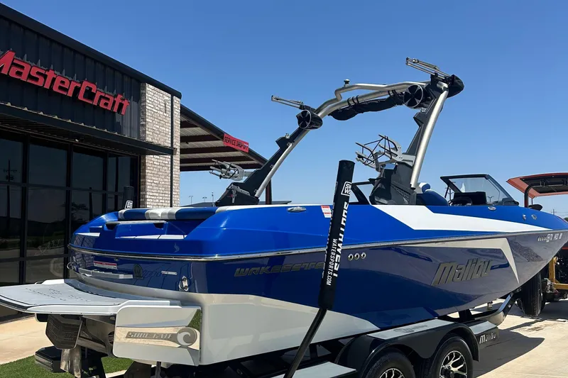 Slide: The Image of 2021 Malibu Wakesetter 21 MLX boat in blue, parked outside a MasterCraft dealership. - 3