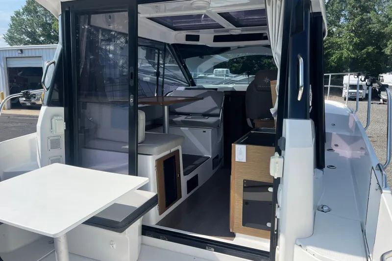 Slide: The Image of 2020 Jeanneau NC 895 boat interior with seating and table, docked outdoors. - 11