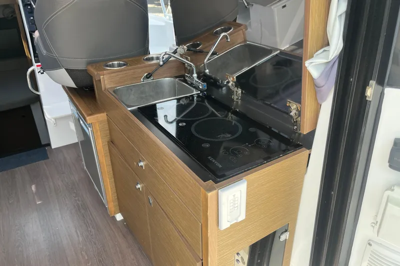 Slide: The Image of Compact kitchen area in a 2020 Jeanneau NC 895 boat, featuring a sink and stove. - 18