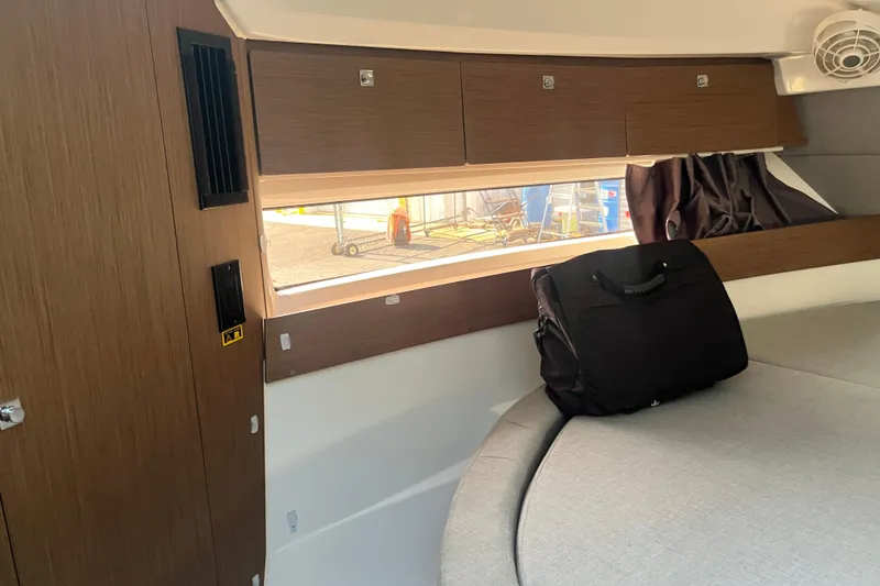 Slide: The Image of Interior of 2020 Jeanneau NC 895 boat with wooden cabinets and a black bag on the bed. - 39