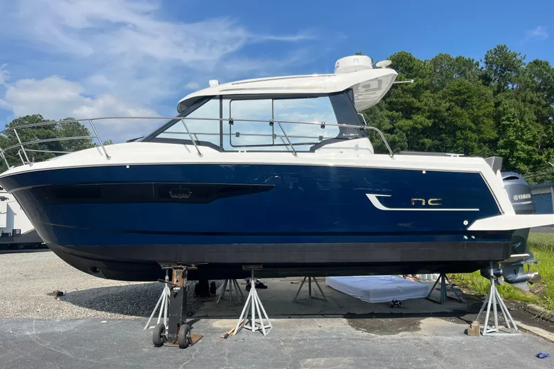 Slide: The Image of 2020 Jeanneau NC 895 boat on stands, blue hull, outdoors, sunny day. - 53