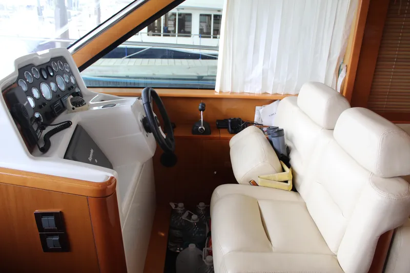 Slide: The Image of 2005 Beneteau Antares 13.80 helm station with white leather seats and control panel. - 17