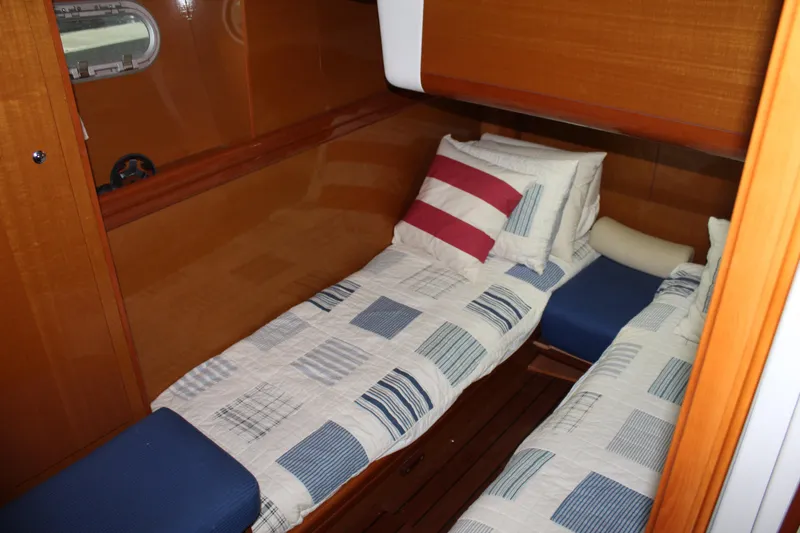Slide: The Image of Twin cabin in 2005 Beneteau Antares 13.80 with wooden interior and nautical-themed bedding. - 30
