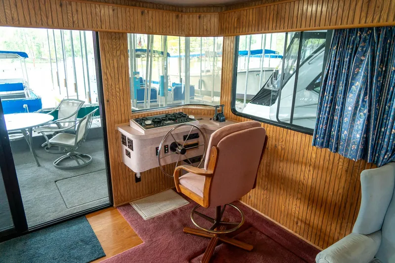 Slide: The Image of 1995 Lakeview 62 x 14 Widebody Houseboat interior with helm, wood paneling, and outdoor seating. - 16