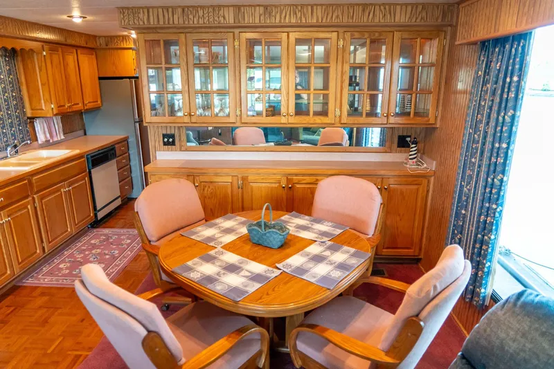 Slide: The Image of 1995 Lakeview houseboat interior with wooden cabinets, dining area, and kitchen. - 21