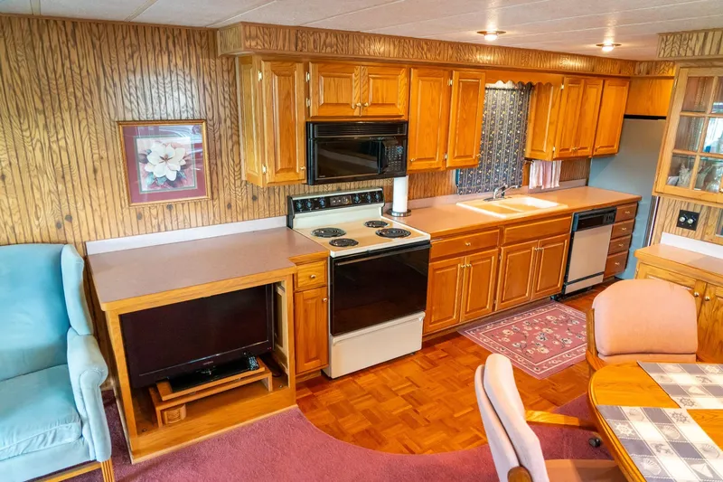 Slide: The Image of 1995 Lakeview houseboat kitchen with wooden cabinets, stove, and dining area. - 23
