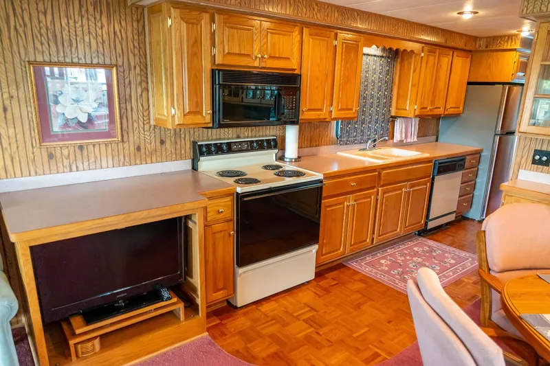 Slide: The Image of 1995 Lakeview houseboat kitchen with wooden cabinets, stove, and stainless steel appliances. - 27
