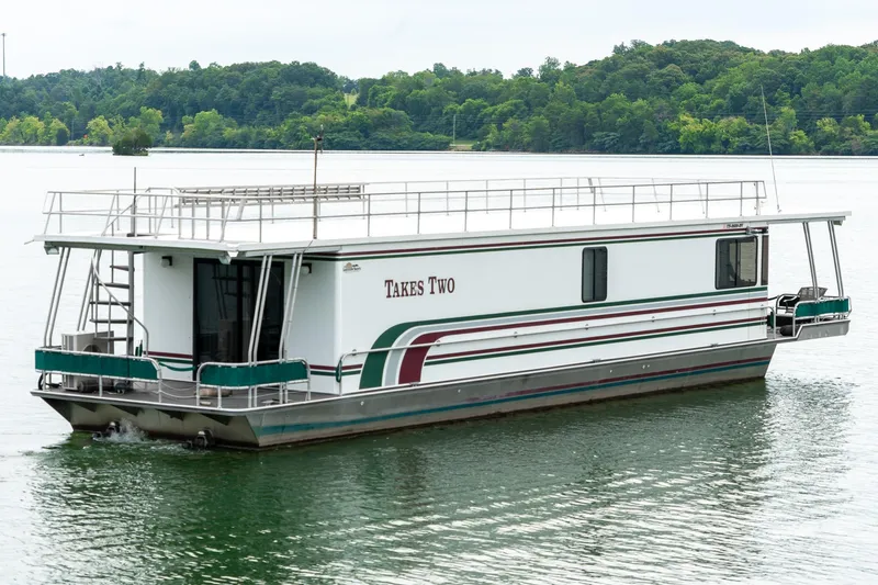 Slide: The Image of 1995 Lakeview 62 x 14 Widebody Houseboat on serene lake with lush green backdrop. - 3