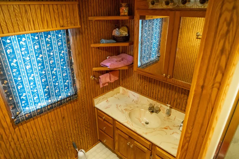 Slide: The Image of 1995 Lakeview houseboat bathroom with wood paneling, blue floral curtains, and marble countertop. - 41