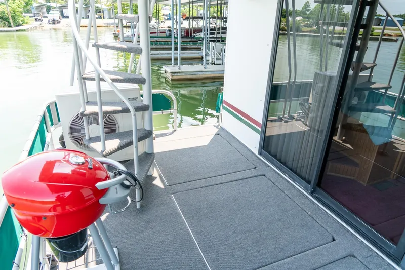 Slide: The Image of 1995 Lakeview 62 x 14 Widebody Houseboat deck with spiral staircase and red grill. - 46