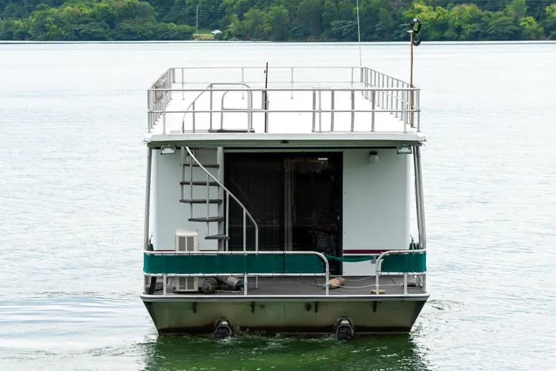 Slide: The Image of 1995 Lakeview 62 x 14 Widebody Houseboat on a serene lake with lush green backdrop. - 7