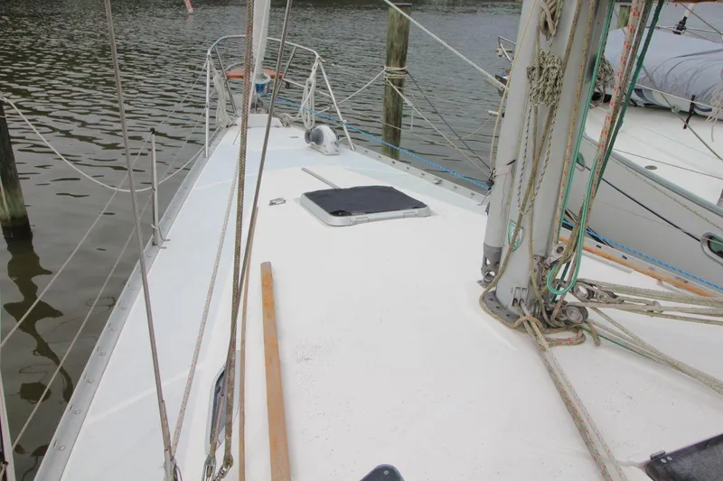 Slide: The Image of 1989 Hunter Legend 35.5 sailboat deck with rigging and hatch, docked by the water. - 10