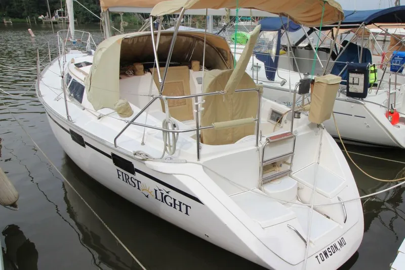 Slide: The Image of 1989 Hunter Legend 35.5 sailboat named "First Light" docked in a marina. - 2