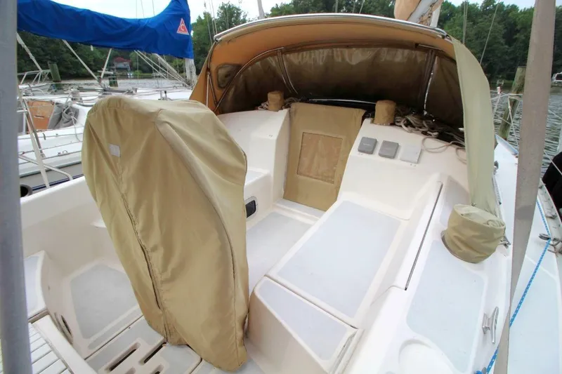Slide: The Image of 1989 Hunter Legend 35.5 sailboat cockpit with beige covers and blue sail in marina. - 8
