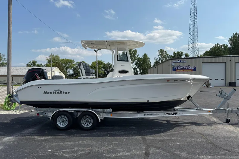 The Image of 2023 NauticStar 24 XS boat on trailer, parked outdoors near Clemons Boats storage facility. - 0