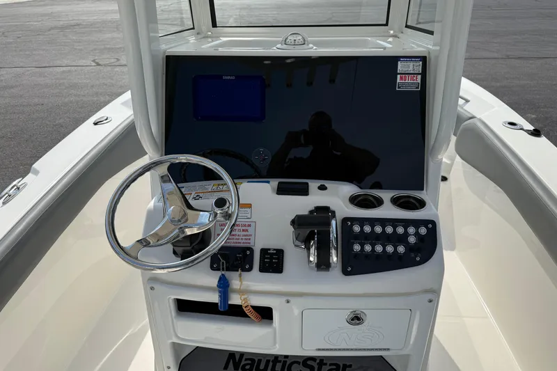 Slide: The Image of 2023 NauticStar 24 XS boat dashboard with steering wheel and control panel. - 12