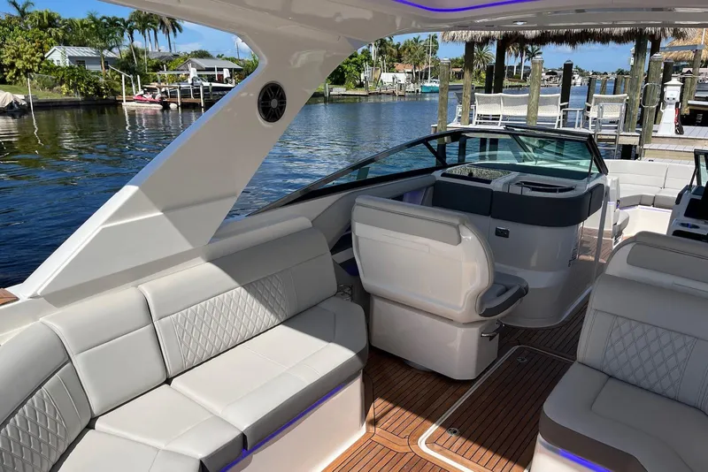 Slide: The Image of 2022 Sea Ray SLX 310 Outboard interior with luxurious seating and waterfront view. - 11