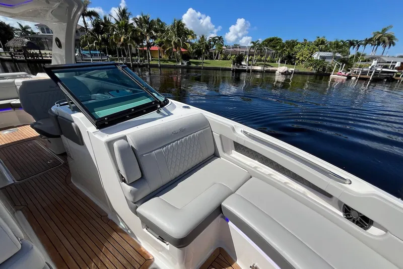 Slide: The Image of 2022 Sea Ray SLX 310 Outboard boat interior with luxurious seating by the water. - 12
