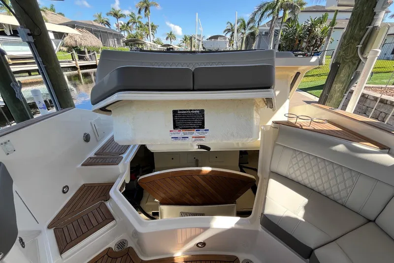 Slide: The Image of 2022 Sea Ray SLX 310 Outboard interior with seating and storage, docked near palm trees. - 17