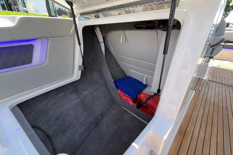 Slide: The Image of 2022 Sea Ray SLX 310 Outboard storage compartment with carpeted interior and safety equipment. - 23