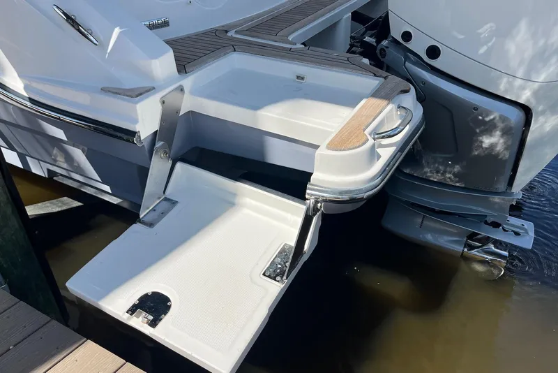 Slide: The Image of 2022 Sea Ray SLX 310 Outboard swim platform with fold-down step in water. - 25