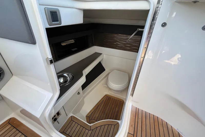 Slide: The Image of 2022 Sea Ray SLX 310 Outboard interior with compact bathroom and wooden flooring. - 26