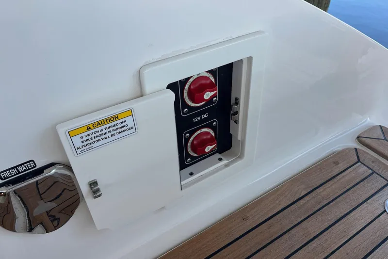 Slide: The Image of 2022 Sea Ray SLX 310 Outboard battery switches and caution label on deck. - 36