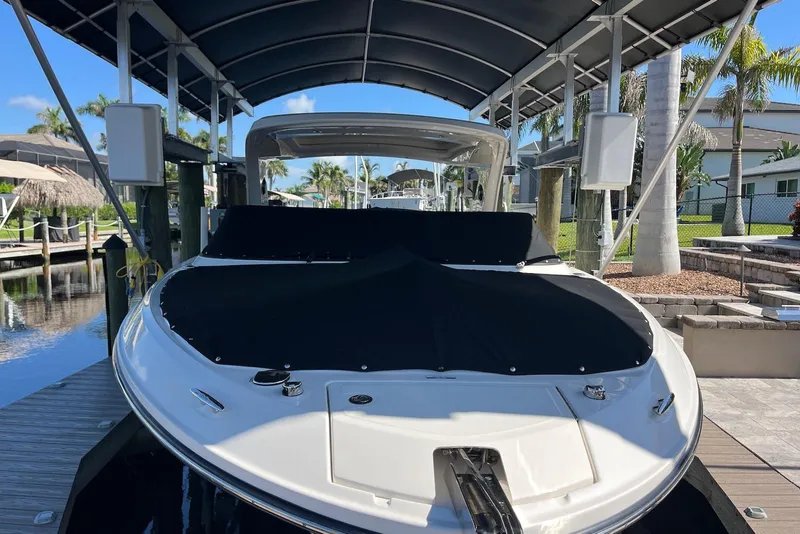 Slide: The Image of 2022 Sea Ray SLX 310 Outboard boat docked under canopy, covered with black tarp. - 39