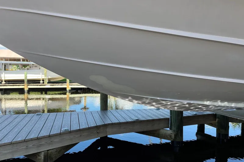 Slide: The Image of 2022 Sea Ray SLX 310 Outboard boat hull above wooden dock, reflecting on water. - 40