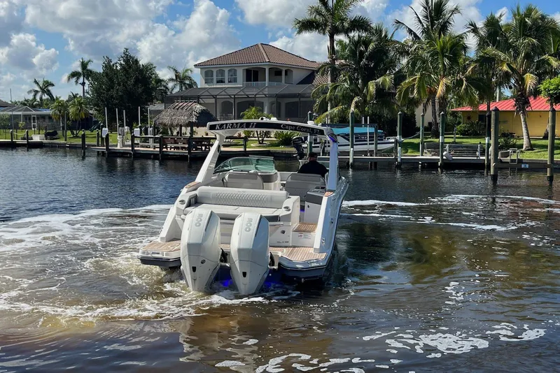Slide: The Image of 2022 Sea Ray SLX 310 Outboard cruising on a sunny waterfront with palm trees. - 7