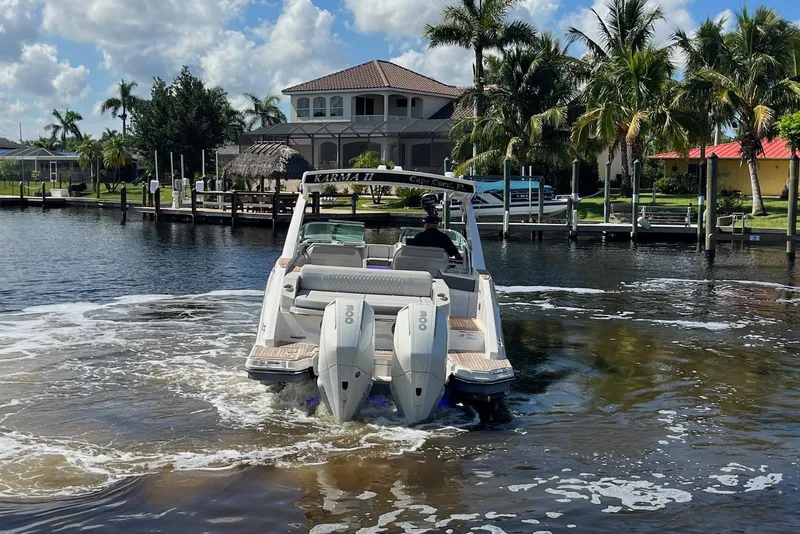 Slide: The Image of 2022 Sea Ray SLX 310 Outboard cruising on a sunny waterfront with palm trees. - 8