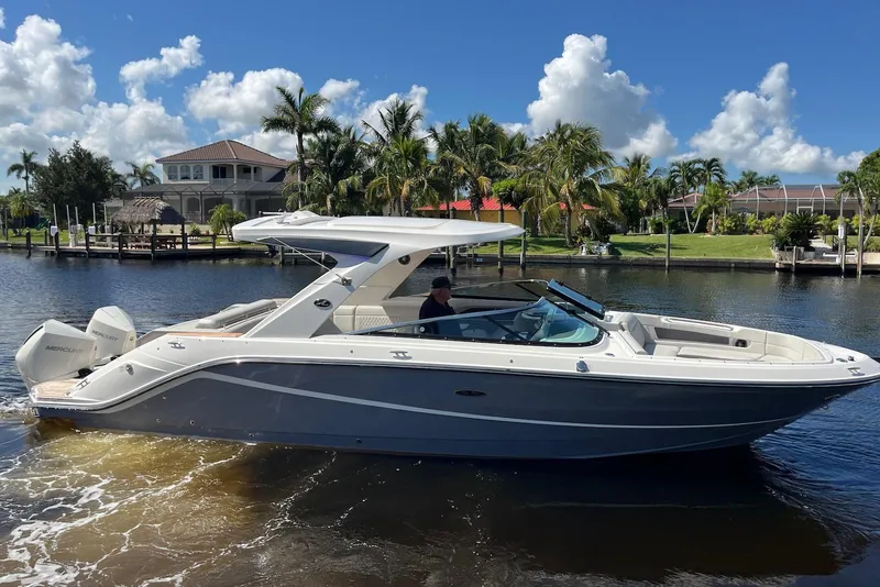 Slide: The Image of 2022 Sea Ray SLX 310 Outboard boat cruising on a sunny day near waterfront homes. - 9