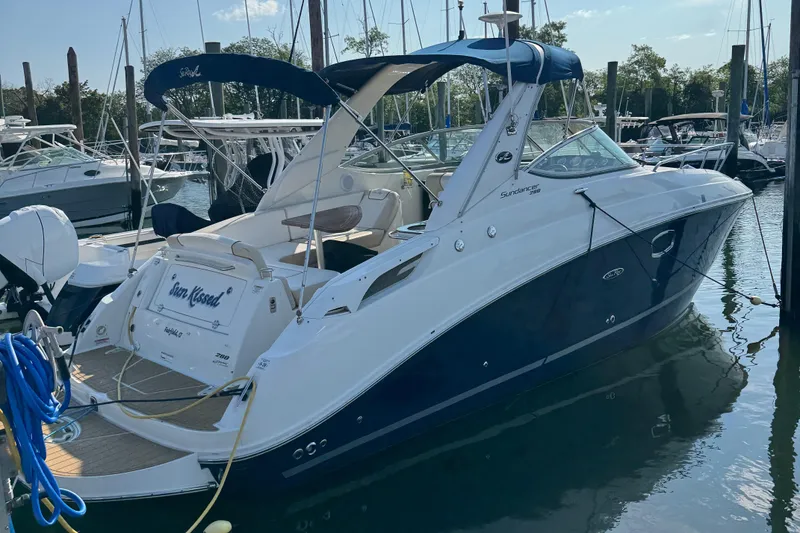 Slide: The Image of 2012 Sea Ray 280 Sundancer boat docked in a marina, featuring sleek design and blue accents. - 1