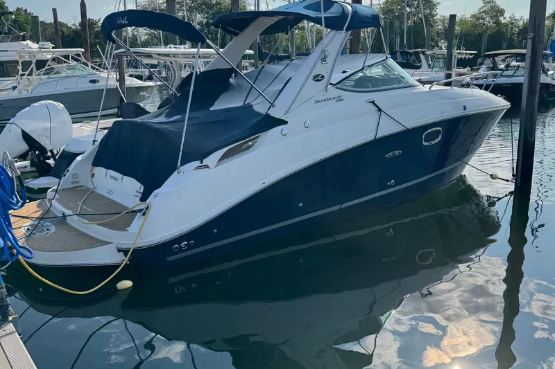 Slide: The Image of 2012 Sea Ray 280 Sundancer boat docked in marina, featuring sleek design and blue hull. - 10