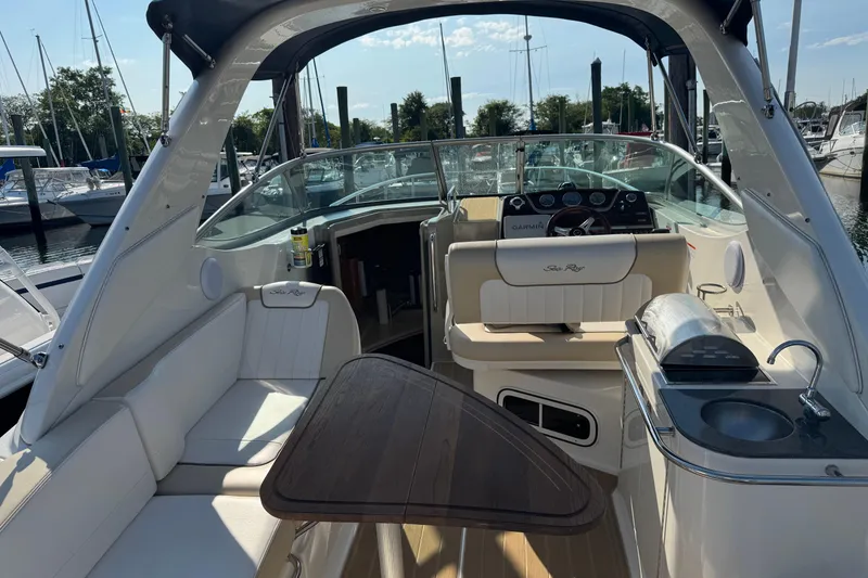 Slide: The Image of 2012 Sea Ray 280 Sundancer interior with seating, table, and helm at marina. - 3