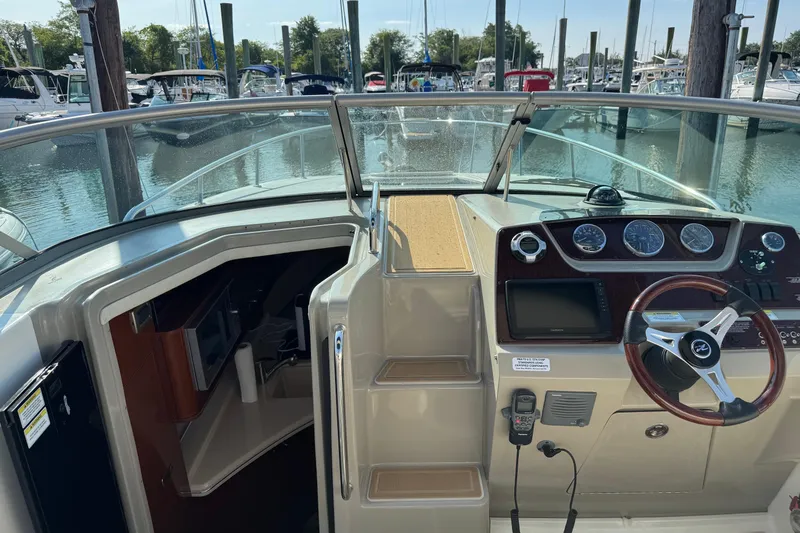 Slide: The Image of 2012 Sea Ray 280 Sundancer cockpit with steering wheel, dashboard, and cabin entrance at marina. - 4