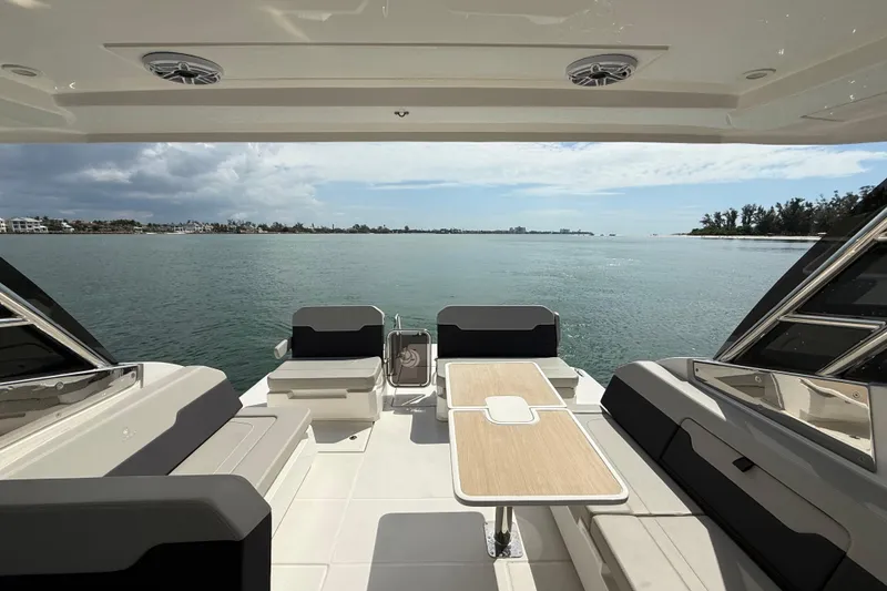 Slide: The Image of Aquila 32 Sport 2025 boat interior with seating and table, overlooking serene water view. - 21