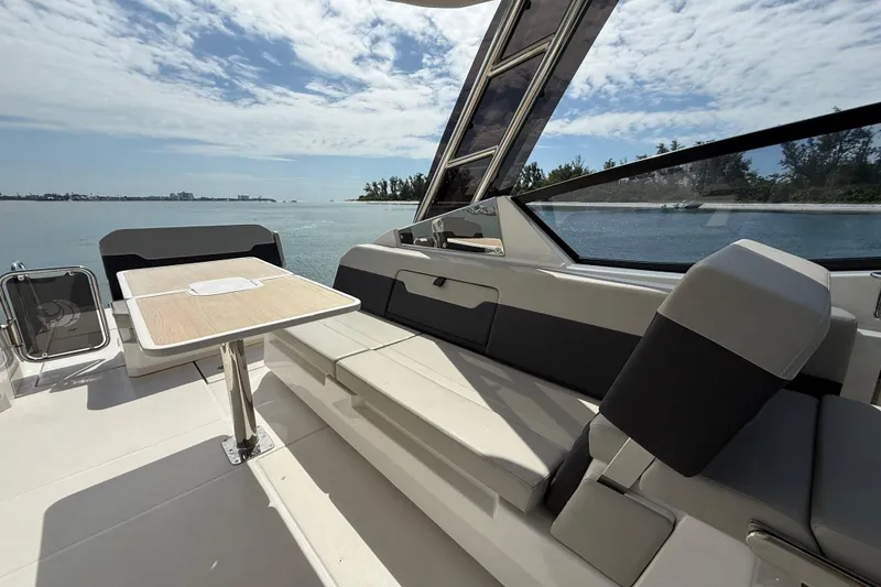 Slide: The Image of 2025 Aquila 32 Sport boat interior with seating and table, overlooking serene water. - 23