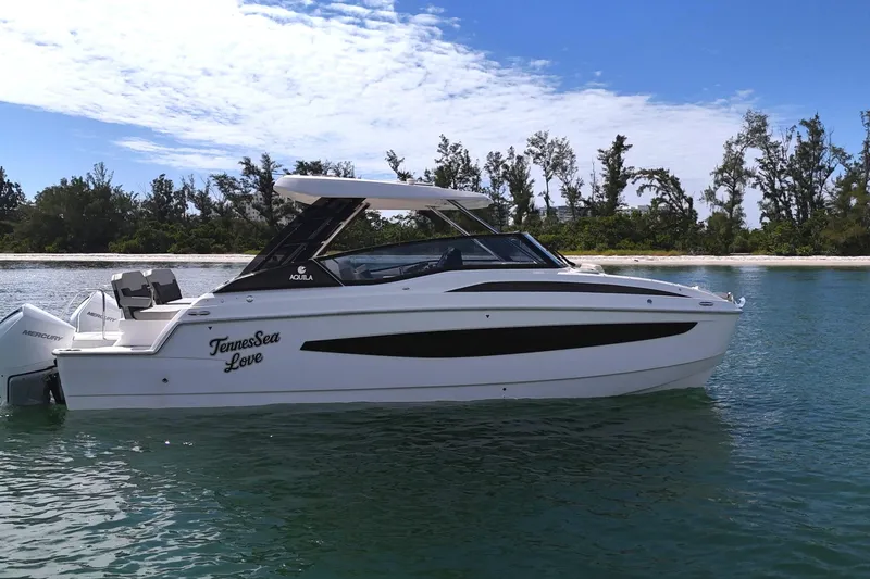 Slide: The Image of 2025 Aquila 32 Sport boat on calm water near a forested shoreline. - 5