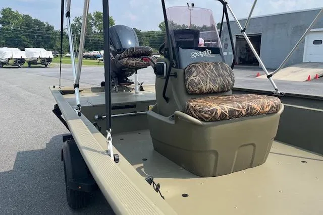 Slide: The Image of 2020 Tracker Grizzly 1860 CC boat with camouflage seats, parked outdoors. - 6
