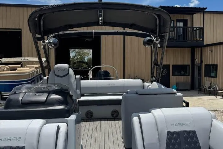 Slide: The Image of 2020 Harris Solstice 250 pontoon boat with sleek seating and canopy, docked near a building. - 9