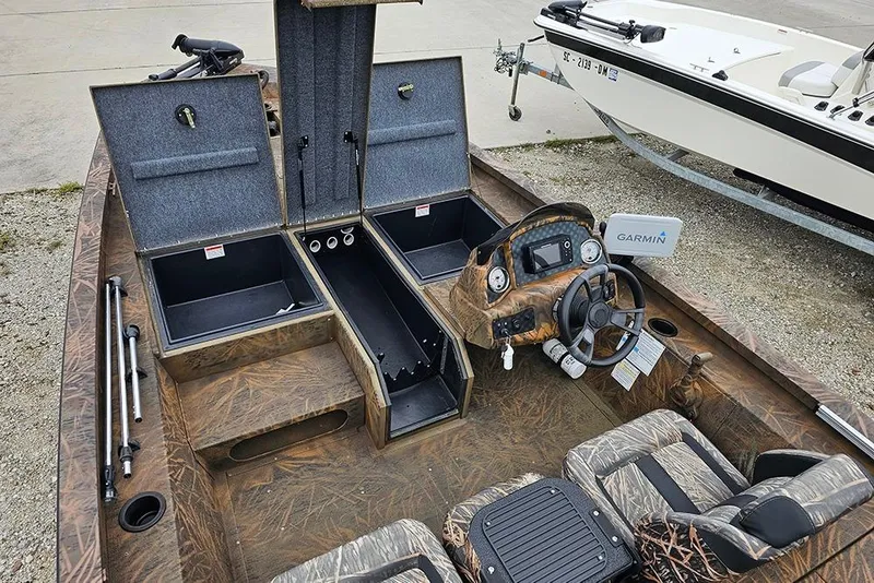 Slide: The Image of 2023 G3 Sportsman 1810 Camo boat interior with open storage compartments and Garmin navigation system. - 16