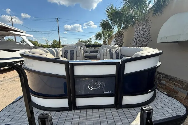 Slide: The Image of 2021 Barletta L23UC pontoon boat with plush seating, docked under a sunny sky. - 2