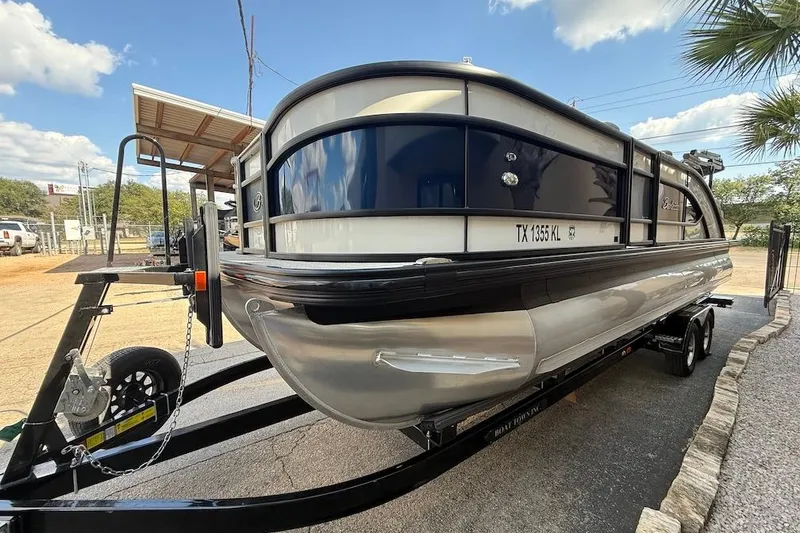 Slide: The Image of 2021 Barletta L23UC pontoon boat on trailer, parked outdoors under a clear sky. - 3