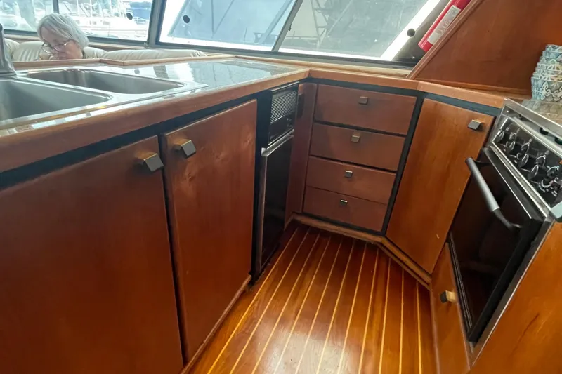 Slide: The Image of 1989 Bayliner Pilothouse 4588 kitchen with wood cabinets and modern appliances. - 11