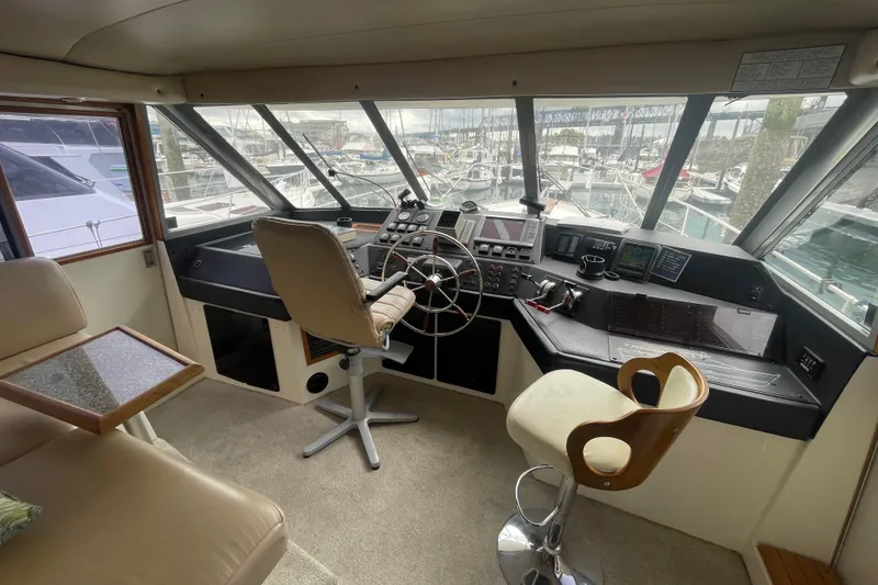 Slide: The Image of Interior of 1989 Bayliner Pilothouse 4588, featuring helm station and seating in marina setting. - 17